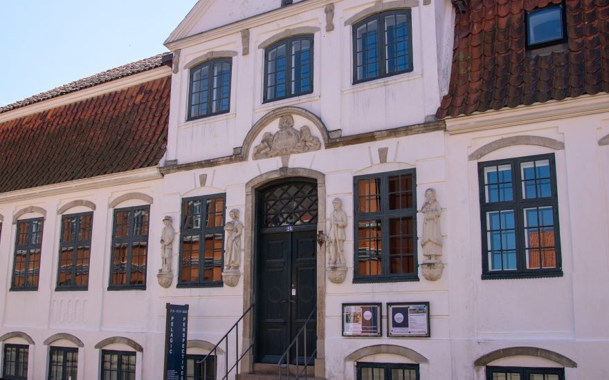 Kongegaardens facade med fire figurer af Marius Hammann